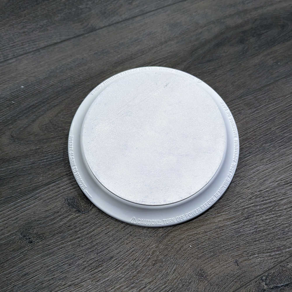 A circular cover for a smoke detector, installed in the existing bracket